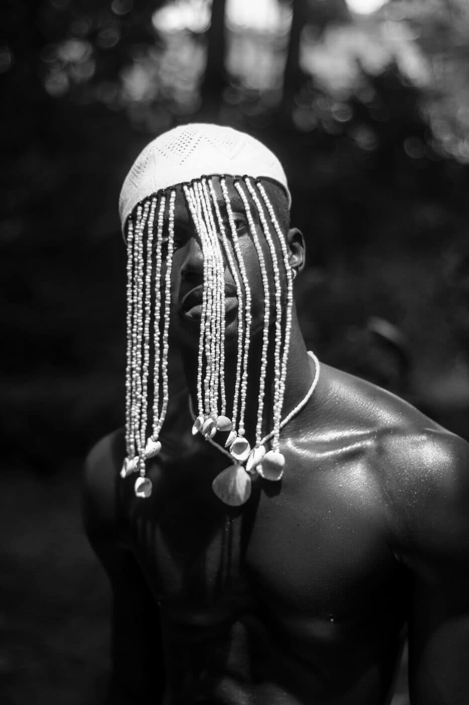 A person wearing a beaded headpiece, photographed in black and white.
