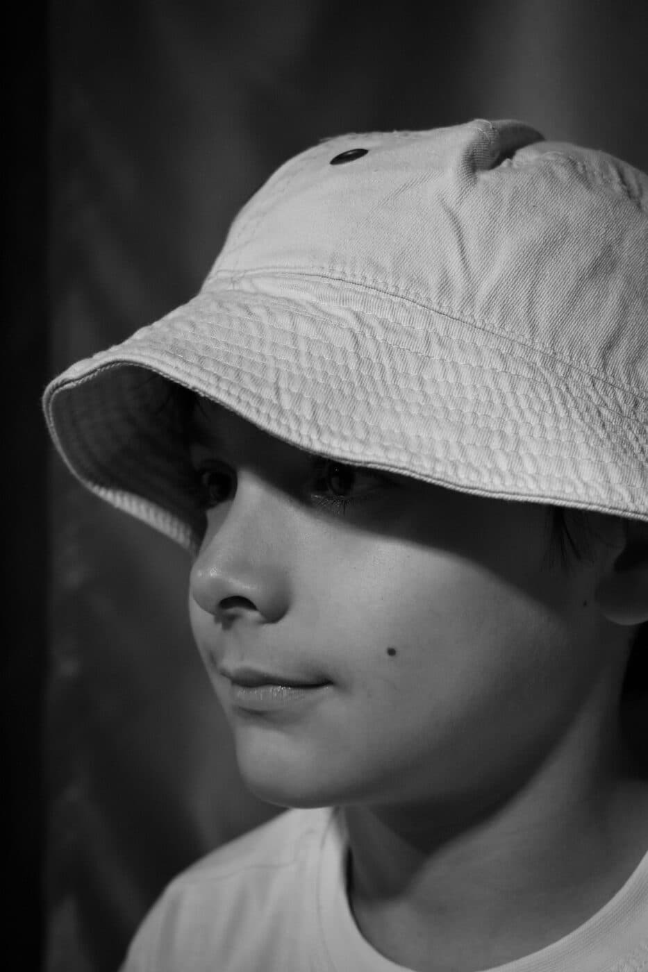 A young person wearing a bucket hat, photographed in black and white.