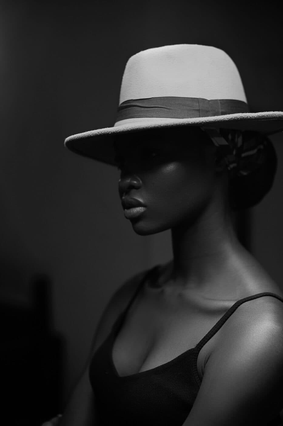 Side profile of a person wearing a light felt fedora, in black and white.